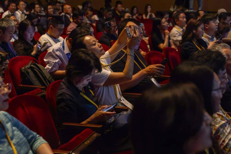 Attendees photograph the stage during a session at the 2026 Frontier Symposium