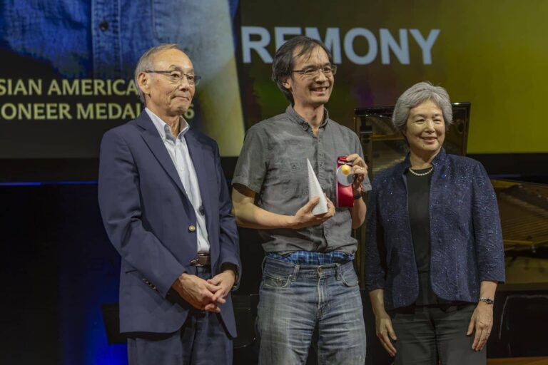 A medalist accepts the 2026 Asian American Pioneer Medal on stage